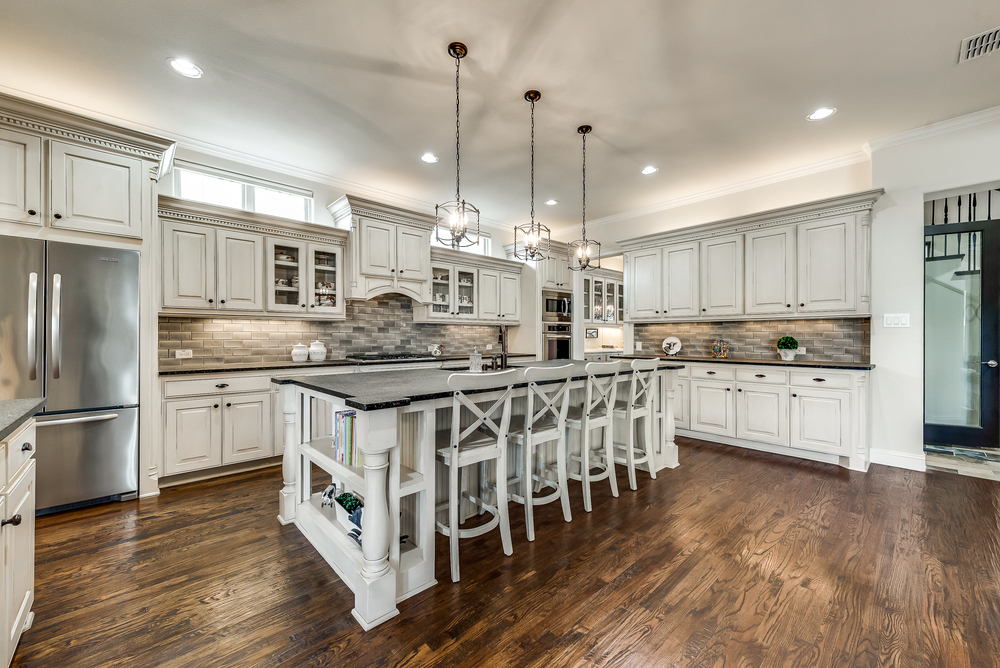    Glass Subway Tile Backsplash and Antiqued Cabinetry with Stunning Millwork 