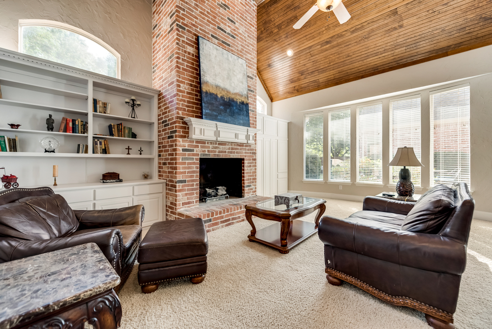    Family Room offers Wood Burning Brick Fireplace White Built In Cabinetry Wall of Windows and Rich Wood Ceiling 