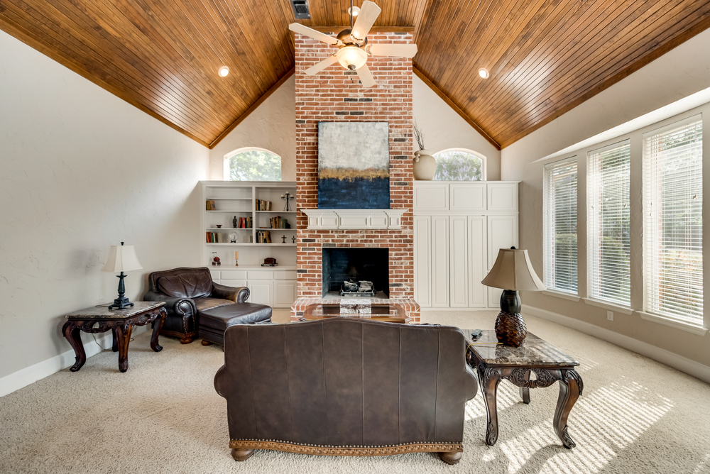    Family Room offers Wood Burning Brick Fireplace White Built In Cabinetry Wall of Windows and Rich Wood Ceiling 